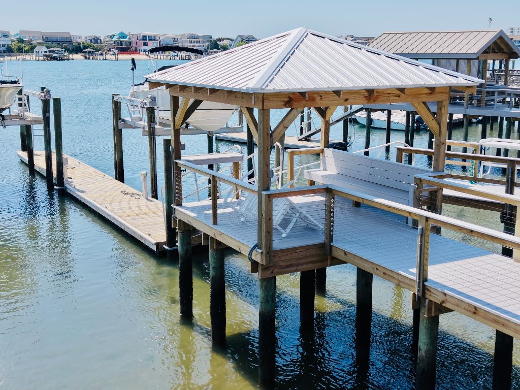 Hip-roof covered dock with cable railings, floating dock, and Adirondack chairs