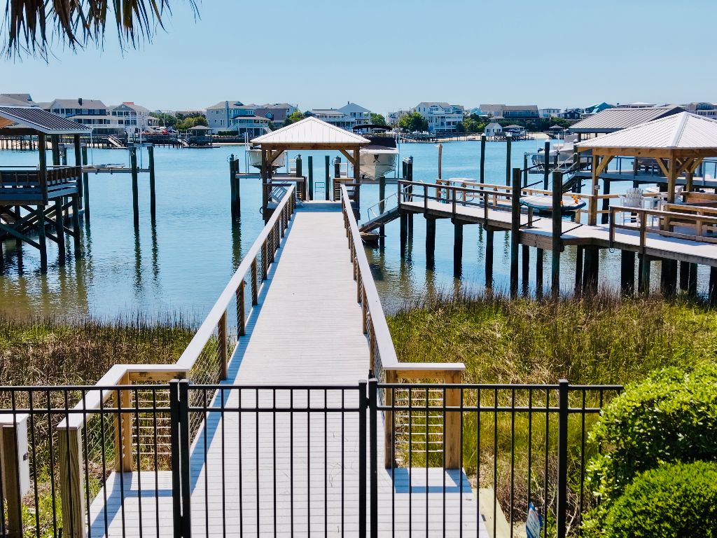 Long composite walkway with aluminum railings and gated entry leading to covered pier